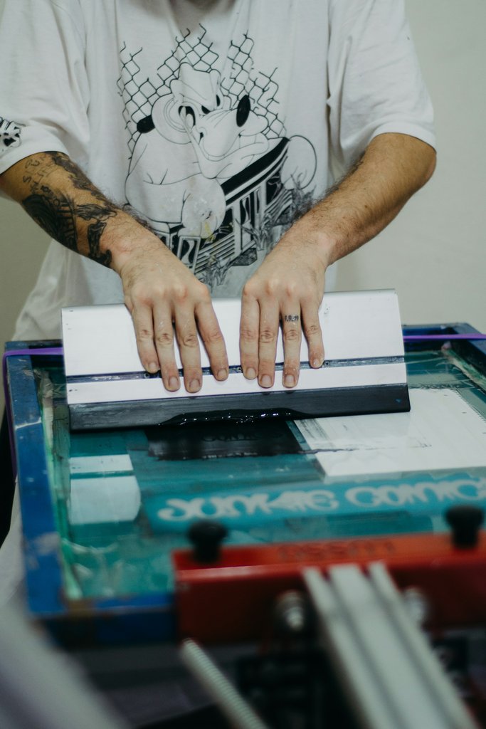 Close-up of hands adjusting a vintage printing press. Industrial machinery in use.